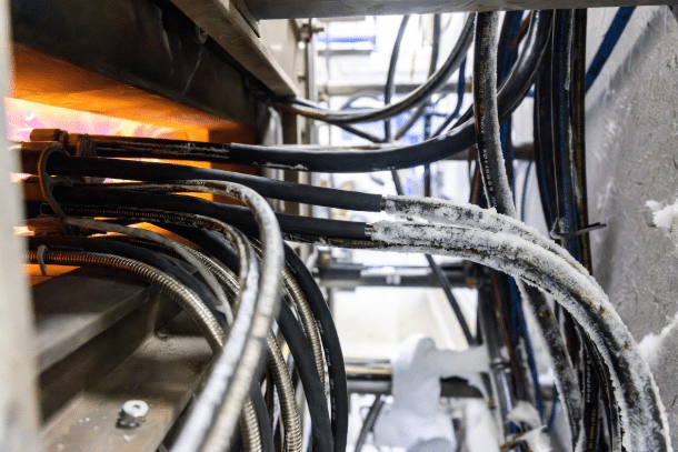 High-temperature silicone cables and flexible custom cables shown in industrial settings with extreme heat from ovens and cold frost conditions, illustrating proper design for temperature ratings in custom cables
