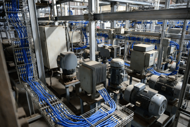 Factory environment showing VFD drives and motors installed near signal cables illustrating common EMI coupling paths in industrial automation