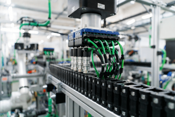 Shielded PROFINET and EtherCAT cables routed through drag chains and robotic arms in an industrial automation factory, demonstrating custom cable specification for motion and network reliability