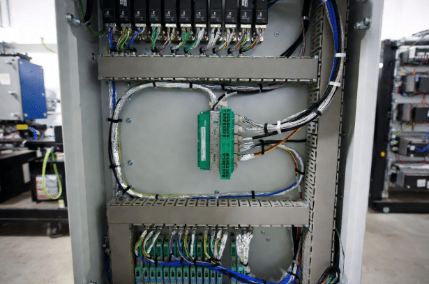 Realistic view of servo drive control cabinet with properly routed custom shielded cables including braided and hybrid types for EMI and noise control in industrial automation systems