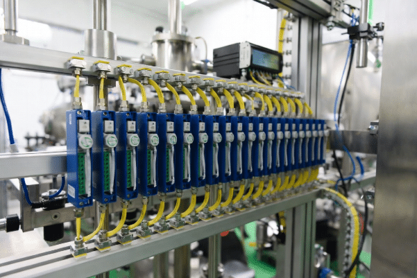 Professional view of Actuator-Sensor Interface AS-i network showing yellow flat cable, multiple piercing-connected slaves, sensors and actuators in a factory automation setting for simplified wiring architecture