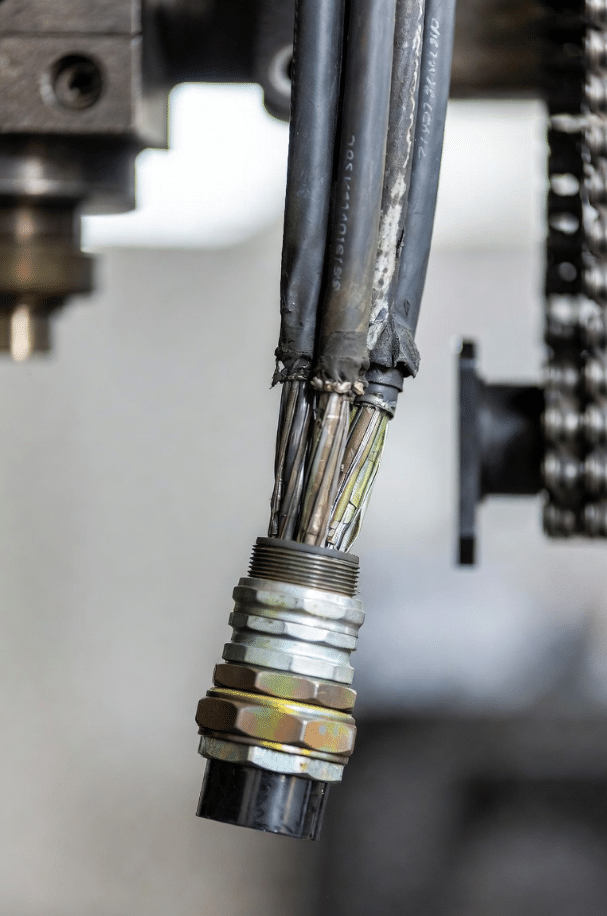 Close-up of high-flex servo cable showing realistic abrasion and strain at bend points in CNC machine cable carrier for common failure mode illustration