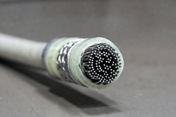 Close-up of buffering fleece, mesh tapes, and PTFE layers absorbing torsional stress and diameter changes inside a robot torsion cable