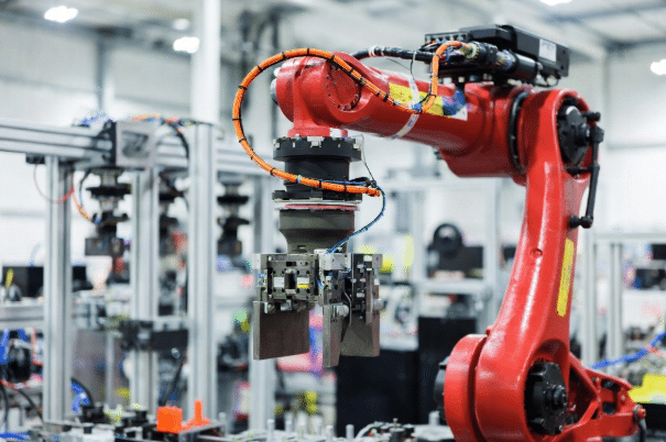 Multi-axis industrial robot arm in automation factory showing single hybrid torsion cable integrating power, control and data lines through tight joints and wrist for space-constrained robotic systems