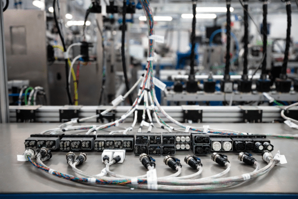Professional view of a complex custom industrial cable harness featuring multiple branches, industrial connectors, shielding, and labels laid out on a workbench, illustrating proper specification for automation systems