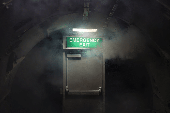 Scene demonstrating improved visibility of emergency lighting and exit signs through lower smoke density from LSZH cables in confined tunnel or corridor during fire scenario simulation