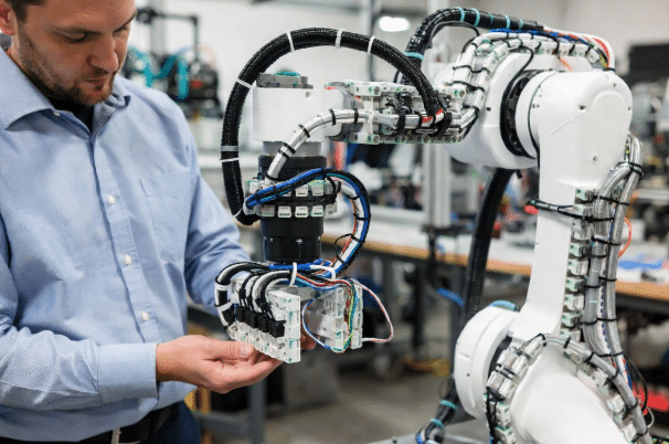 Robotics engineer examining modular segmented torsion cable harness with junction boxes on prototype compact robot, showing practical design and installation best practices