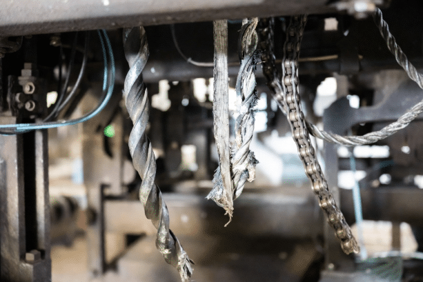Close-up of common drag chain cable failures including jacket abrasion, corkscrewing, and conductor issues inside energy chains for motion profile mismatch education