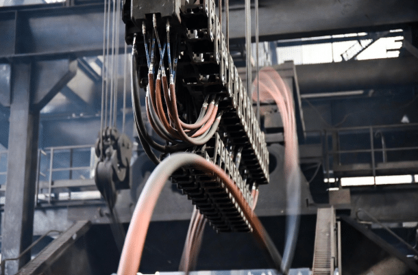 Close-up of high-flex silicone cables in a moving cable carrier on crane equipment inside a steel mill, highlighting flexibility and heat resistance