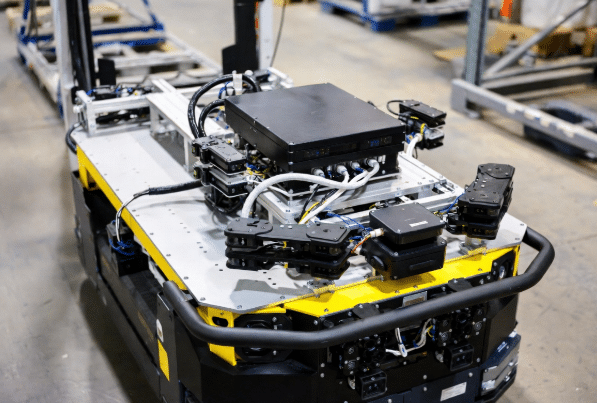 Automated guided vehicle (AGV) navigating warehouse aisles with visible flexible sensor cabling supporting navigation and safety sensors in material handling operations