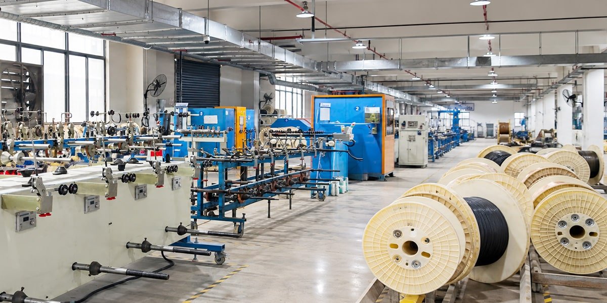 Panoramic view of HULK's expansive stranding workshop featuring rows of heavy-duty blue cable twisting machines and extensive inventory of cable reels, demonstrating high-capacity production capabilities for large-scale industrial orders.