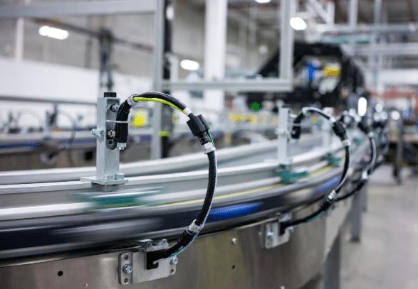 Close-up view of durable flexible sensor cables properly routed along moving conveyor equipment with vibration-resistant connectors in material handling automation