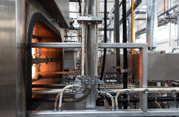 Realistic view of high-temperature furnace or oven zone in manufacturing plant showing flexible silicone cables routed near hot equipment for reliable performance in demanding conditions