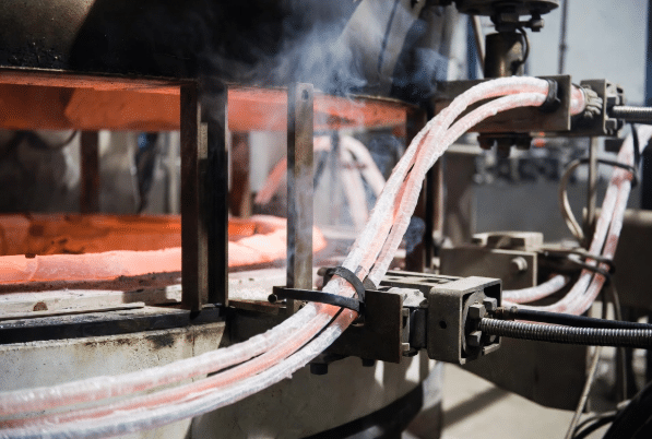 Professional view of flexible high-temperature silicone cables with durable insulation routed securely around hot furnace equipment in an industrial setting, illustrating proper design for extreme heat environments