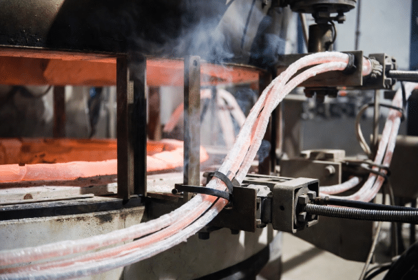 Professional view of flexible high-temperature silicone cables with durable insulation routed securely around hot furnace equipment in an industrial setting, illustrating proper design for extreme heat environments