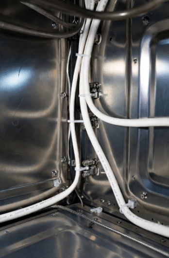 Close-up of durable white high-temperature silicone cables routed inside modern appliances near heating elements, demonstrating professional installation for safety and reliability in heating equipment
