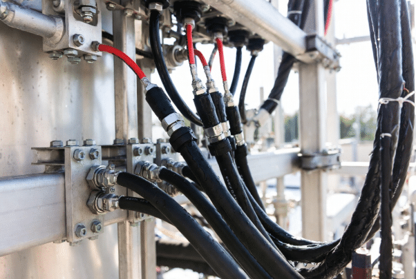 Professional view of durable black and red high-temperature silicone cables mounted outdoors under sunlight with moisture, demonstrating UV and weather resistance for industrial and renewable energy applications