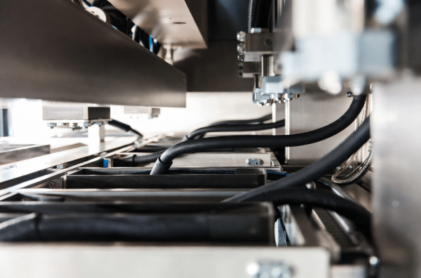 Realistic view of durable high-temperature silicone cables neatly routed with gentle bends, protective sleeving, and secure management inside compact high-heat industrial equipment for reliable performance