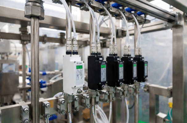 Close-up of IO-Link enabled sensors and actuators connected via high-flex M12 cables on food processing or automation machinery, demonstrating clean cabling layout and reliable connections in a modern factory setting
