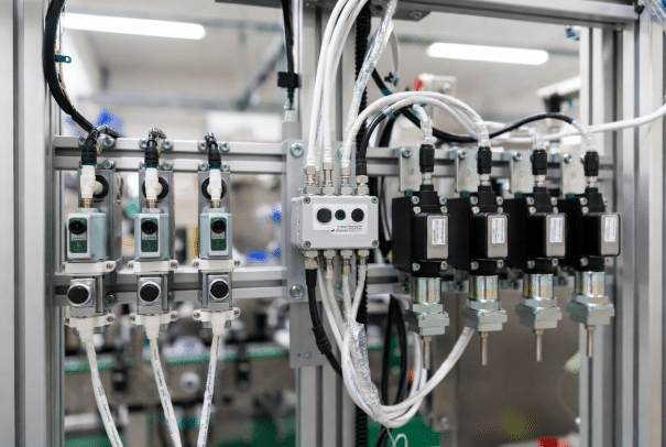 Close-up of proximity sensors and pneumatic actuators connected by M8 M12 sensor and actuator cables in a real industrial packaging line, demonstrating signal transmission in automation systems