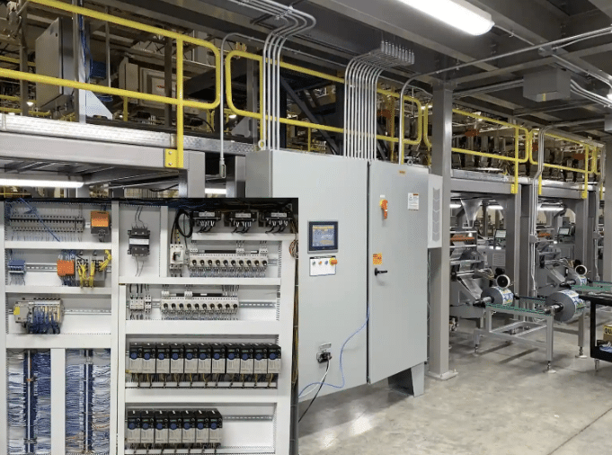 Detailed view of open control cabinets and cable routing in a factory setting, showing organized halogen-free automation cables for fire safety and equipment protection