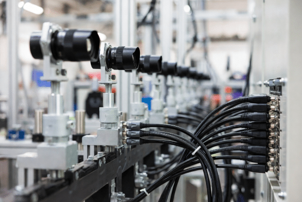 Multiple industrial cameras installed on production line machinery with durable high-flex shielded cables and secure connectors, illustrating reliable machine vision cabling setup