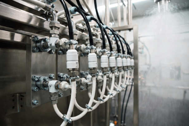 Realistic view of protected sensor cable connections with flexible Hulk-style cables, glands and drip loops on stainless steel machinery in a food processing washdown area, highlighting prevention of water ingress and contamination
