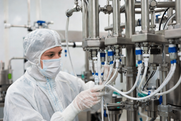 Technician wearing gloves carefully routing and inspecting hygienic sensor and actuator cables with proper glands on food processing equipment, emphasizing quality control and clean installation practices