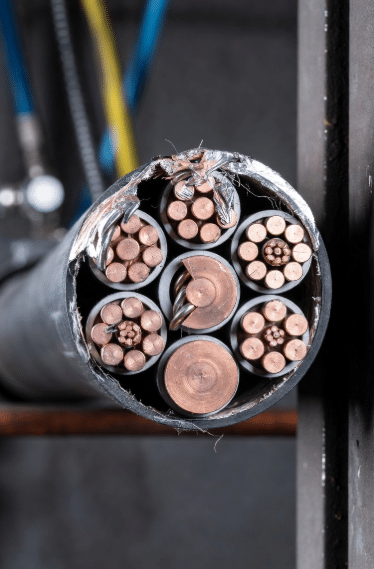 Close-up cross-section of a continuous flex drag chain cable with fatigued and broken copper conductors at bend zones, highlighting fatigue failure in industrial cable troubleshooting