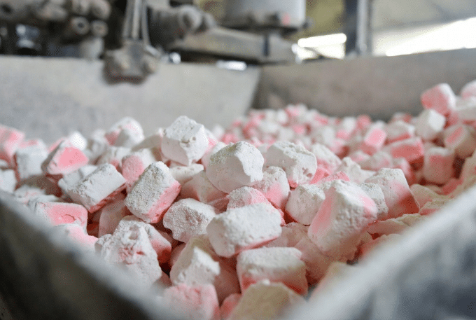Close-up of pink and white LSZH and HFFR halogen-free cable compound pellets on industrial workbench, highlighting material composition for low smoke zero halogen cable production