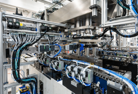 Professional view of large industrial automation machine featuring short sensor actuator cables connected to distributed I/O modules, flexible high-performance cables in drag chains, and network backbone for efficient layout in modern manufacturing