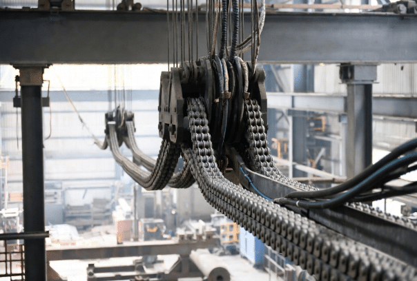 Extended industrial long-travel drag chain in guide trough supporting heavy cables on large gantry, key for long travel drag chain cable design considerations