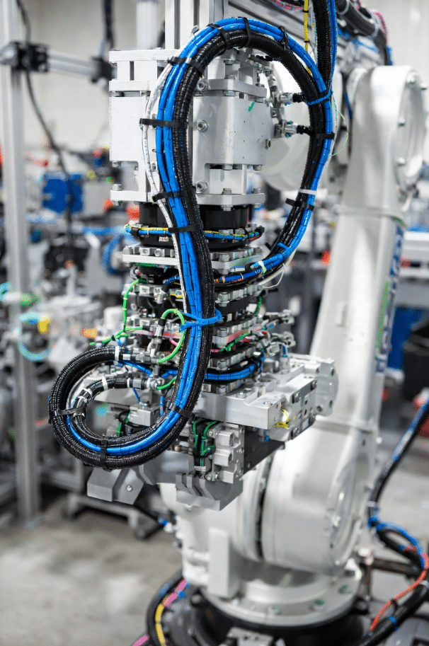 Industrial robot arm cable management dress pack showing separated routing for power and shielded signal cables to minimize EMI coupling and support torsion motion