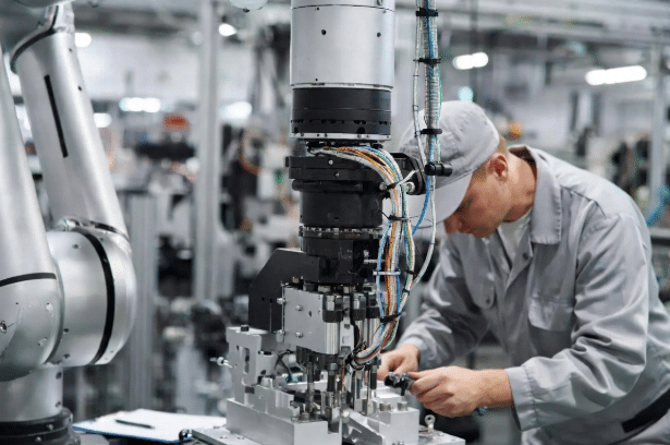 Technician performing cycle-based inspection on torsion-stressed robot cables at industrial 6-axis arm, supporting service life planning and reliability