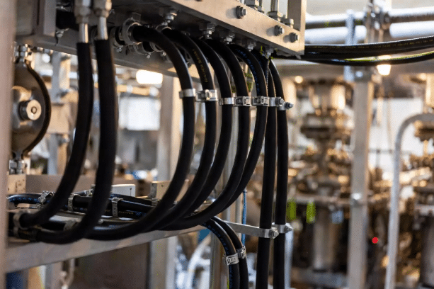 Realistic industrial installation of silicone cables demonstrating minimum bend radius, clamping, and secure routing in high-temperature process equipment to ensure mechanical reliability
