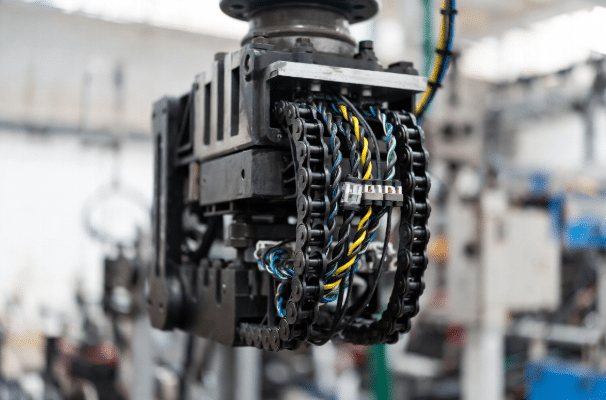 High-flex torsion cables with protective jackets routing inside drag chain on moving robotic arm, demonstrating mechanical stress in industrial setting