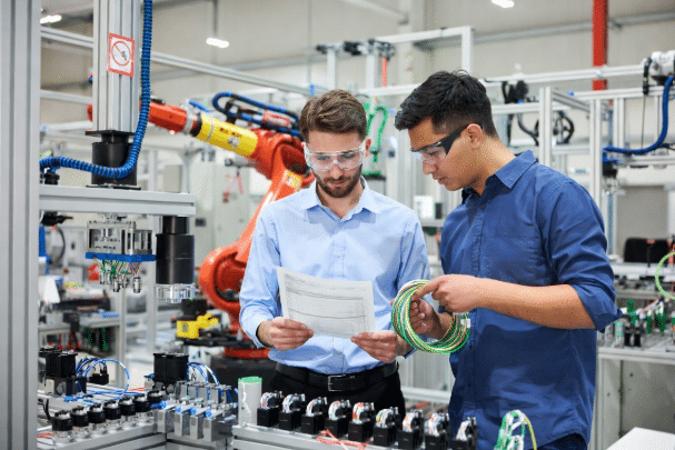 Team of engineers examining robot torsion cable datasheets and samples in modern automation facility, emphasizing proper specification process for flex life