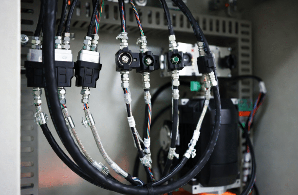 Professional view of custom servo power cables and feedback/encoder cables with connectors attached to a servo motor and drive unit, illustrating high-precision motion control cabling in an industrial setting