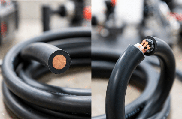 Realistic side-by-side industrial photo comparing rigid standard heat-resistant cable with highly flexible custom silicone cable, showing cross-sections and material properties for engineering selection