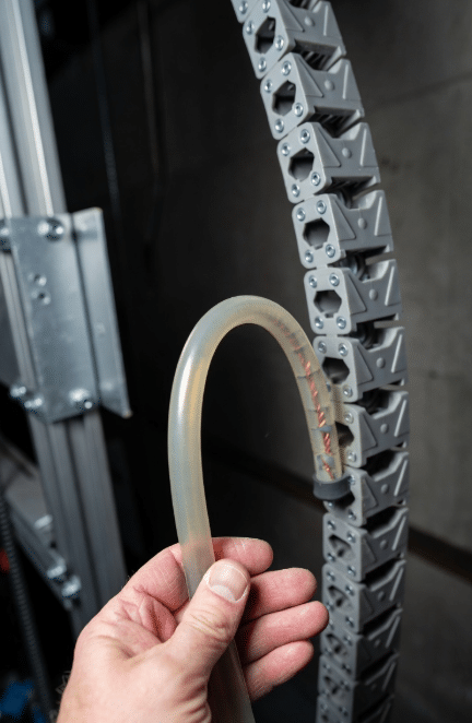 Flexible silicone cable manually bent next to industrial cable carrier system illustrating difference between static pliability and engineered dynamic flex resistance for motion applications