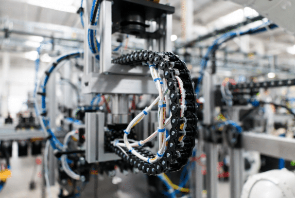 High-flex silicone cables routed through cable carrier on moving robotic arm in automation factory, demonstrating mechanical stress and proper dynamic flexibility in industrial environment