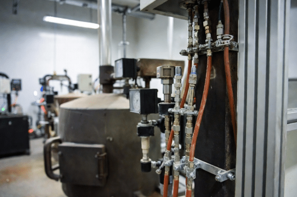 High-temperature silicone cables connected to industrial sensors on a large ceramic kiln in a manufacturing plant, showing reliable performance in extreme heat