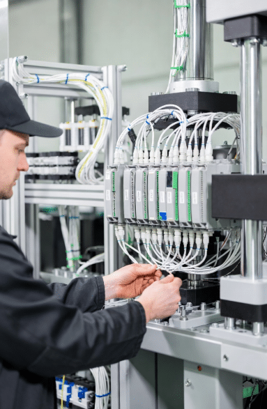 Factory technician checking connections of high-flex sensor and actuator cables to distributed I/O module on large machinery, demonstrating practical layout and quality installation in industrial automation