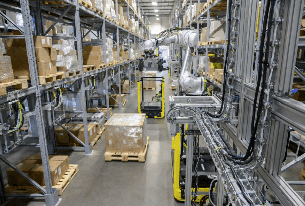 Professional view of AGVs and robotic arms operating in a warehouse with clearly visible custom flexible cables and drag chain management systems for robotics and material handling automation