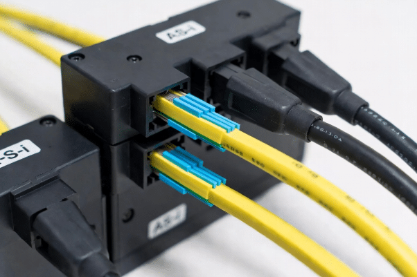 Close-up of yellow AS-i cable and black auxiliary cable with AS-i slave modules connected via piercing technology, demonstrating easy installation for sensors and actuators in industrial cabling