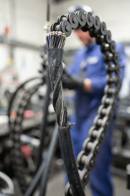 Close-up of high-flex industrial cable showing jacket abrasion and stress inside moving energy chain, highlighting mechanical causes of signal integrity problems in cable carriers
