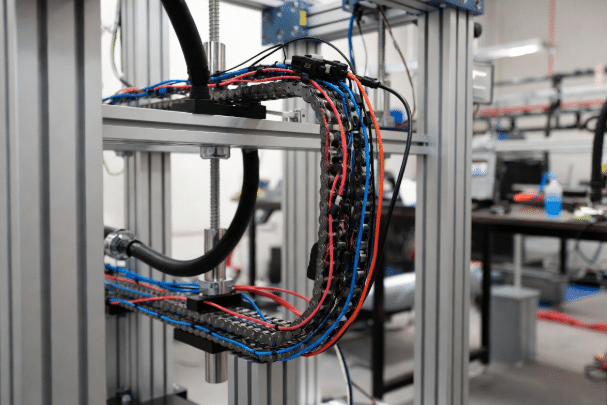 Detailed view of drag chain cable prototype testing rig monitoring continuity and mechanical performance under realistic stroke, speed, and bend radius conditions for motion control systems