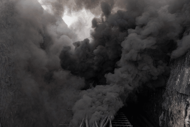 Photorealistic view of thick black smoke filling a confined cable tunnel with burning PVC cables, illustrating poor visibility and risks in enclosed environments for food processing or industrial automation facilities
