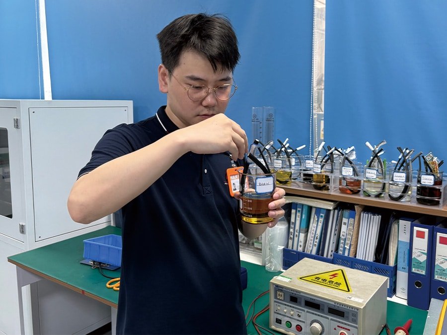 A HULK engineer conducting a chemical resistance test by immersing cable samples into beakers containing various industrial oils and solvents; this process evaluates the cable jacket's ability to resist swelling, corrosion, and degradation when exposed to harsh chemical environments like machining fluids or lubricants.