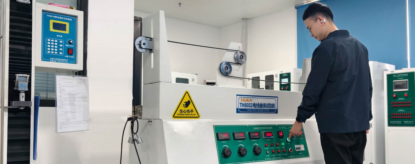 A HULK engineer conducting customer-specific cable validation in a laboratory using a TH8032 Wire Flexure Tester; this tailored testing approach ensures cables meet unique operational requirements for bending, motion, and durability in real-world applications.